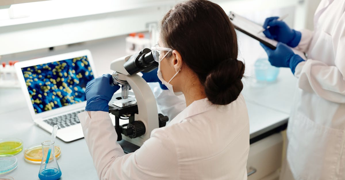 Scientifiques en blouse blanche analysant des échantillons en laboratoire avec des microscopes